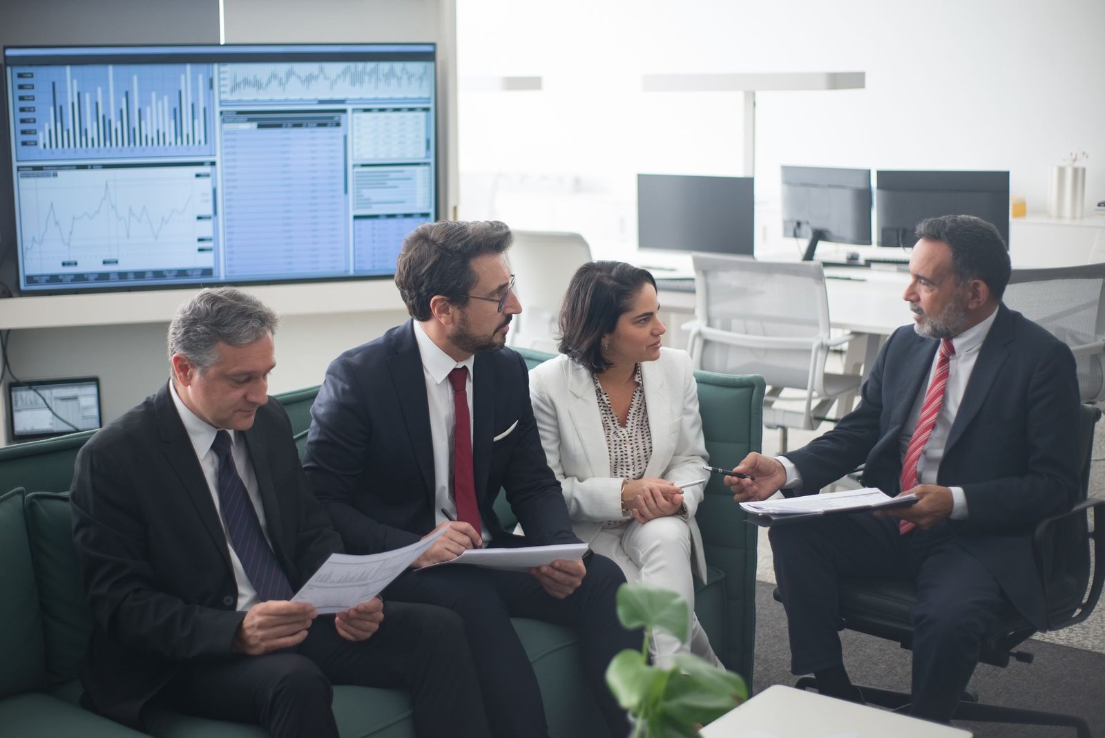 Finance advisors reviewing reports and dashboards with executives in a boardroom